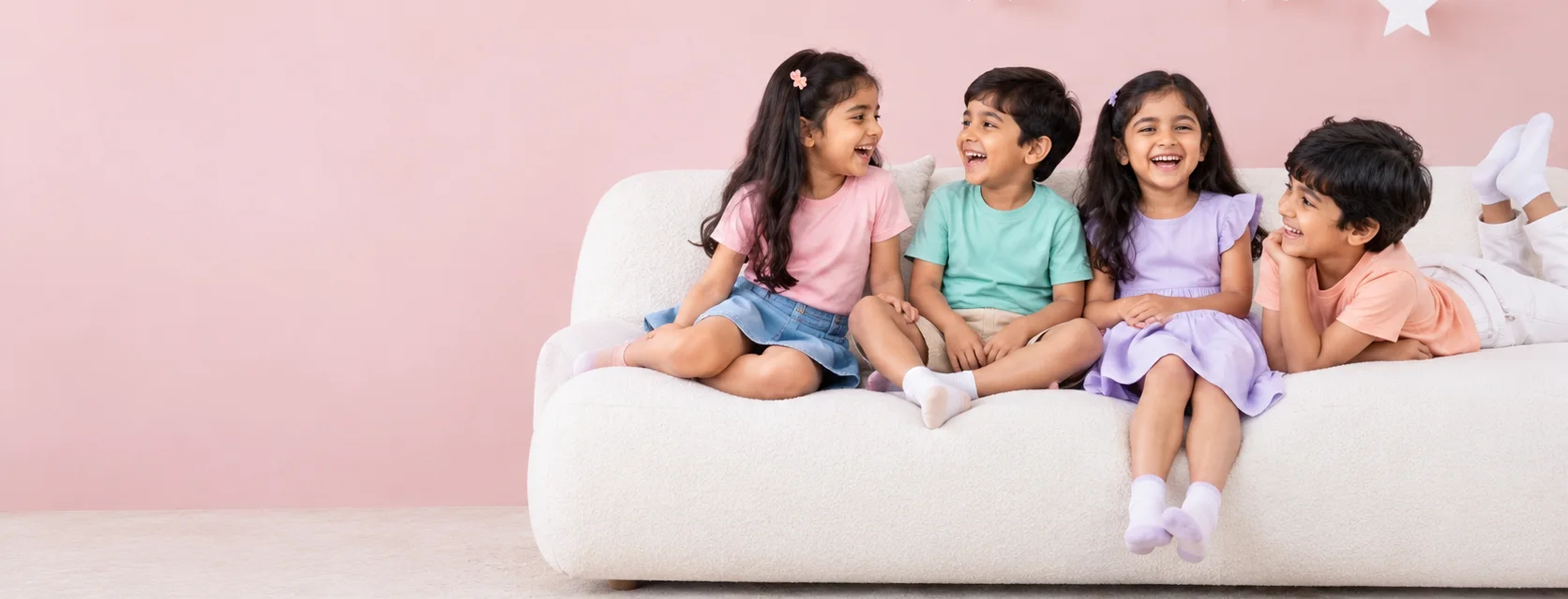 Four happy kids laughing on a white sofa